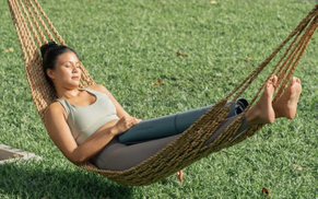Potret wanita sukan dewasa Asia yang cantik memakai bra sukan berehat mengambil tidur tidur buaian yang tenang di luar.jpg