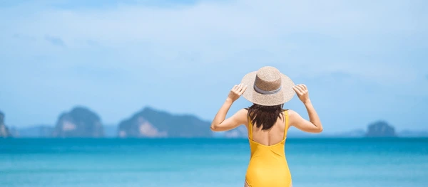 woman tourist yellow swimsuit hat